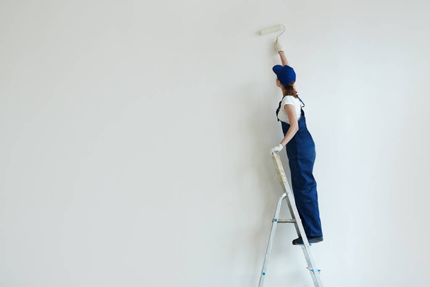 Vrouw schildert muur - Foto, afbeelding