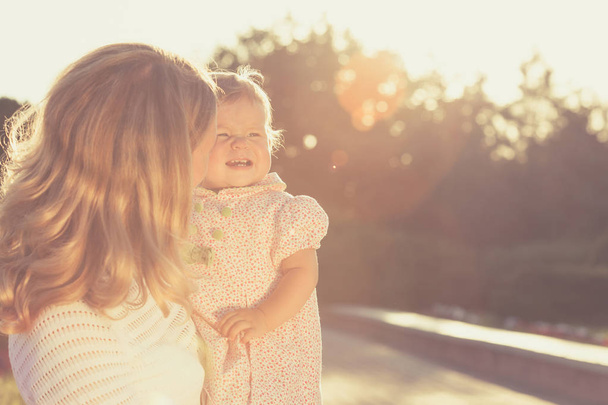 Happy mother and daughter playing in park. - 写真・画像