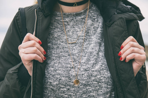 Herbst Mode Outfit Detail. Frau in herbstlichem Outfit, stylischer Bomberjacke und grauem Pullover. trägt trendigen Schmuck - eine schwarze Choker-Halskette. Warme Instagram-Grade. - Foto, Bild