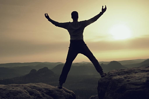 glückliche Mann mit erhobenen Armen Geste Triumph auf exponierter Klippe. Wanderer befriedigen Silhouette auf Sandsteinfelsen mit Blick auf hügelige Landschaft.  - Foto, Bild