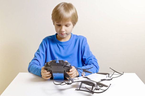 Kis gyerek fog játszani a quadcopter drone otthon. Fiú tartja a rádió távvezérlő - Fotó, kép