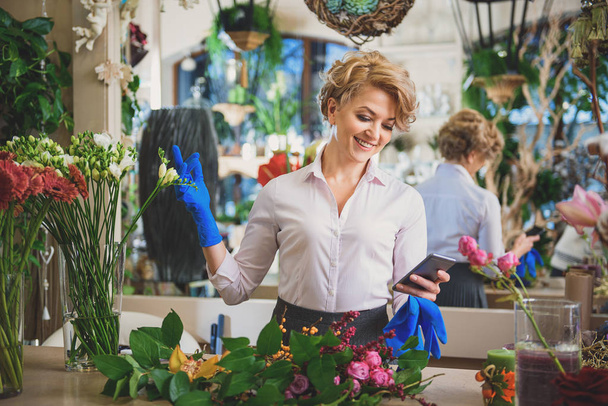 Cheerful female florist messaging on mobile phone - Фото, зображення