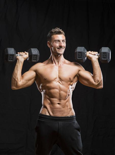 Muscular bodybuilder holding dumbbells weights - Photo, Image