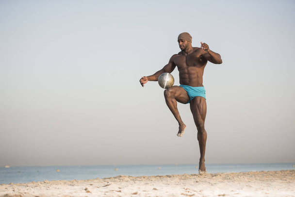 mies potkiminen pallo rannalla
 - Valokuva, kuva