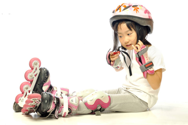 Asiática niña está usando patines y protección
  - Foto, Imagen