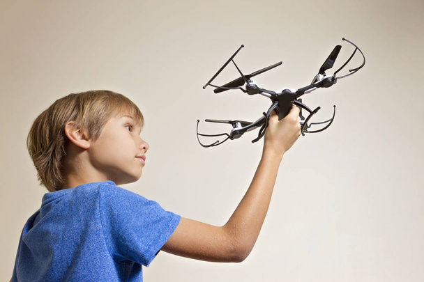 Schoolboy kid playing with drone. Boy holding quadcopter in his hand, preparing to fly - 写真・画像