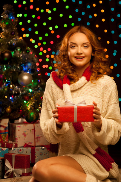 Young smiling woman holding red christmas gift - Fotoğraf, Görsel