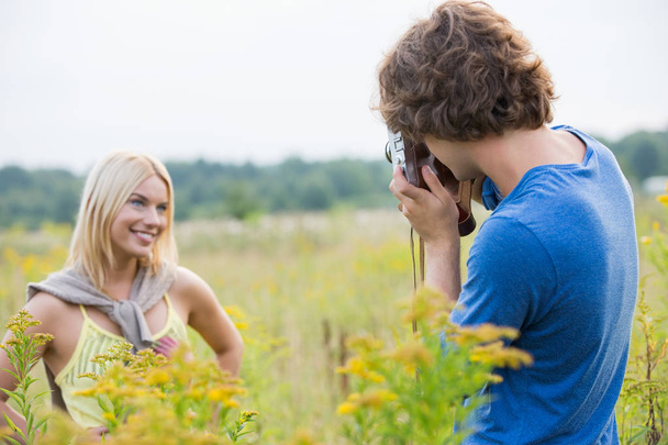 man photographing girlfriend in field - Zdjęcie, obraz