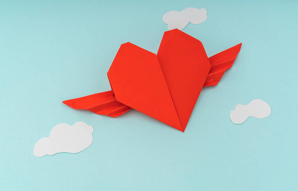 Red paper origami heart with wings and cloud on blue background  - Φωτογραφία, εικόνα