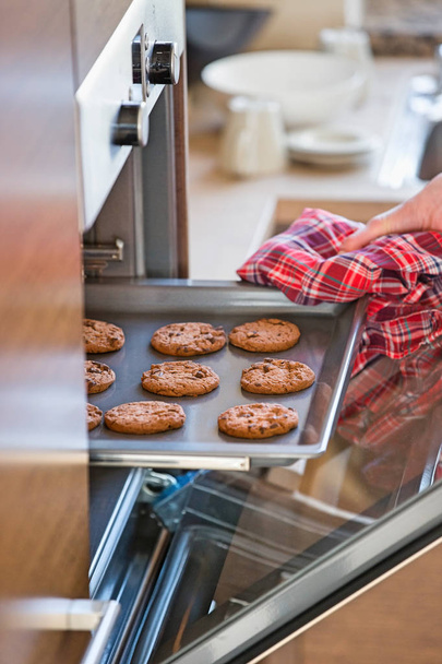 Hand removing cookie tray from oven - Fotografie, Obrázek