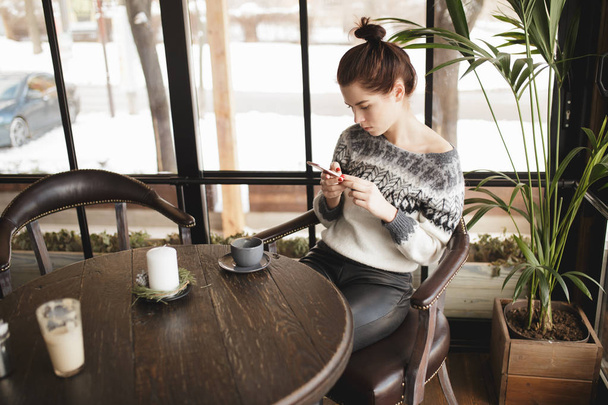 Woman typing text on smartphone in a cafe while coffee is cools - Фото, зображення