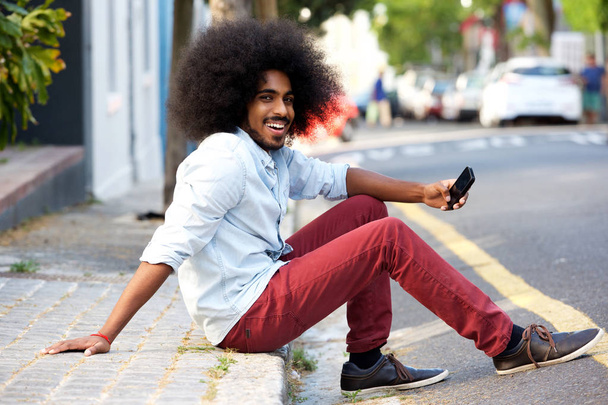 mężczyzna z telefonu komórkowego siedzi na chodniku - Zdjęcie, obraz