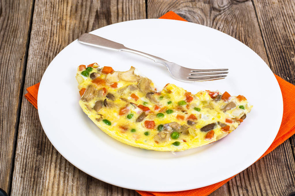 ein halbes Omelett mit Gemüse auf einem weißen Teller - Foto, Bild
