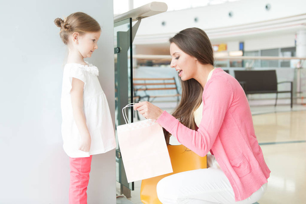 Mother giving daughter shopping bag    - Фото, зображення