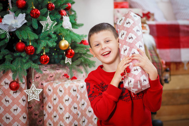Boy with xmas gifts on wooden background - Фото, изображение