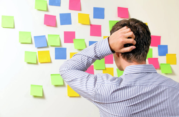 Businessman looking at wall of sticky notes  - Photo, Image
