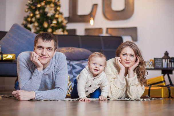 Happy family is lying on carpet tree and smiling - Fotó, kép