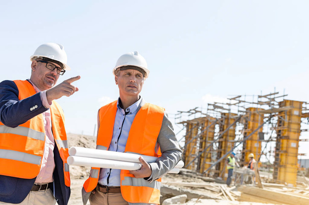 Male engineers discussing at construction site - Foto, afbeelding