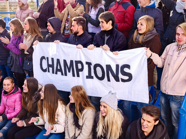 Juichende fans in het stadion bedrijf kampioen banner. - Foto, afbeelding