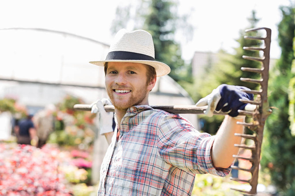 Smiling gardener carrying rake  - Fotografie, Obrázek