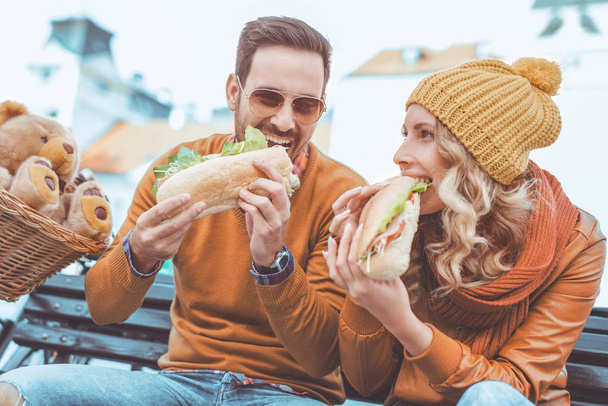 屋外のサンドイッチを食べて幸せな若いカップル - 写真・画像