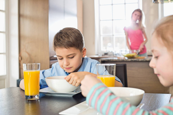 Siblings having breakfast at table - Valokuva, kuva