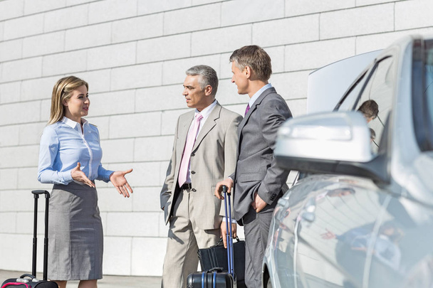Businesspeople discussing outside car - Foto, afbeelding