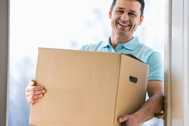 Happy man carrying cardboard box  - Zdjęcie, obraz