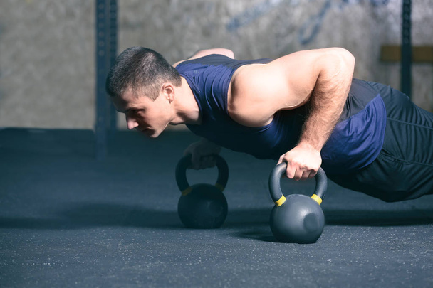 Young handsome man doing push-ups in gym - Photo, image