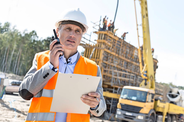 Supervisor using walkie-talkie at construction site - Photo, Image