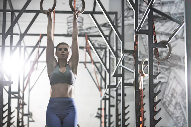 Confident woman exercising with gymnastic rings - Photo, Image