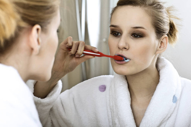 Woman in bathroom brushing teeth - Fotó, kép