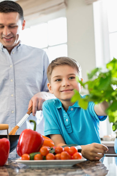 Niño con padre preparando comida en la cocina
 - Foto, imagen