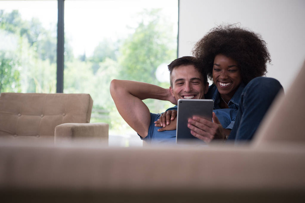 casal multiétnico relaxante em casa com computadores tablet
 - Foto, Imagem