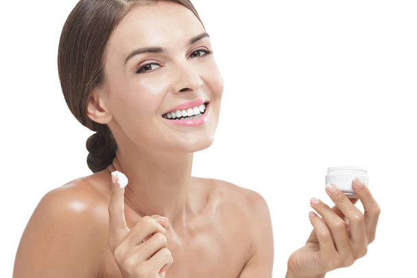 beautiful woman smiling while taking some facial cream - 写真・画像