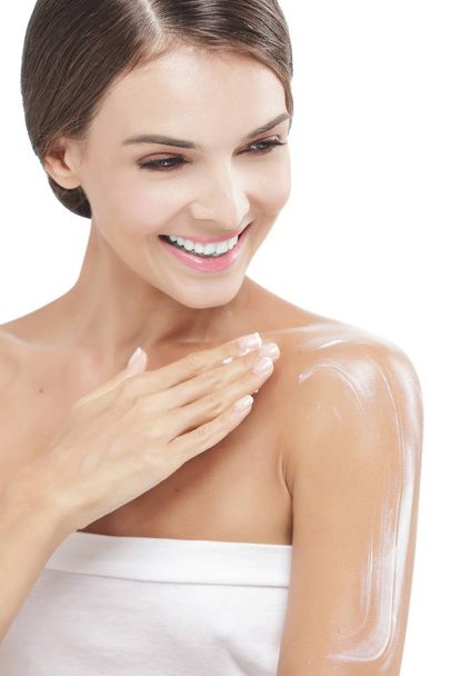beautiful woman applying body lotion to her arms while smiling - Fotó, kép