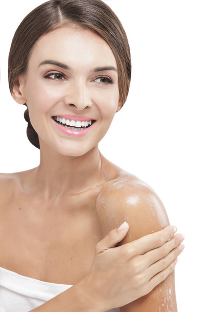 beautiful woman applying body lotion to her arms while smiling - Fotoğraf, Görsel