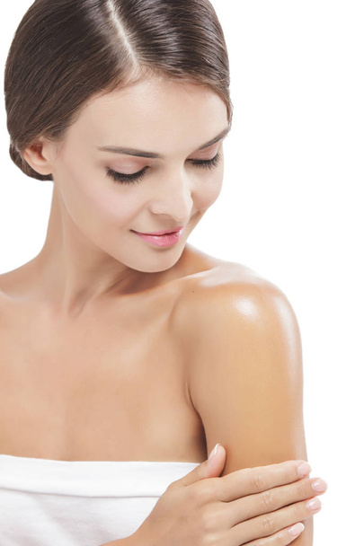 beautiful woman applying body lotion to her arms while smiling - Foto, imagen