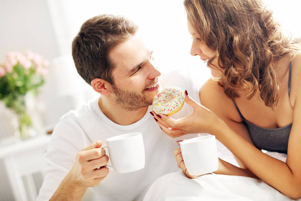Young couple eating breakfast in bed - Photo, Image