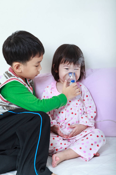 Asijská dívka s respirační nemoci pomáhal bratr s inhalační maskou v nemocnici. - Fotografie, Obrázek