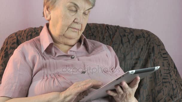 Aged woman 80s holds the silver tablet computer - Πλάνα, βίντεο