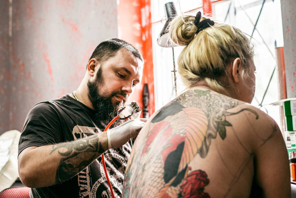 процесс создания татуировки на спине девушки
 - Фото, изображение