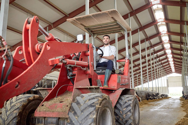man or farmer driving tractor at farm - Zdjęcie, obraz