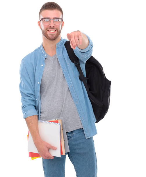 Young male student with a school bag holding books and pointing you isolated on white background - Foto, Bild