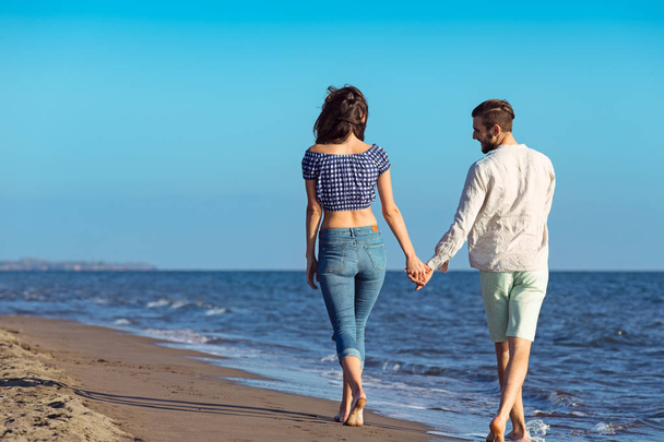 happy interracial couple walking on beach. - Фото, изображение