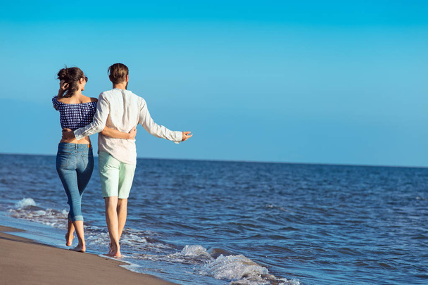 Happy interracial couple walking on beach. - Fotoğraf, Görsel