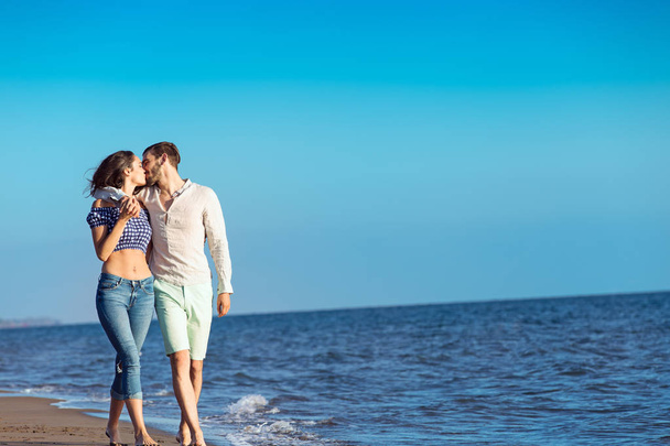 Happy interracial couple walking on beach. - Zdjęcie, obraz