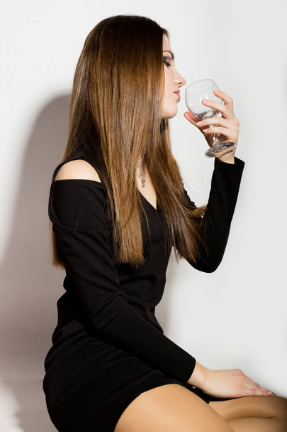 Fashion business beautiful young women in a little black dress with accessories, holding an empty wine glass - Photo, Image