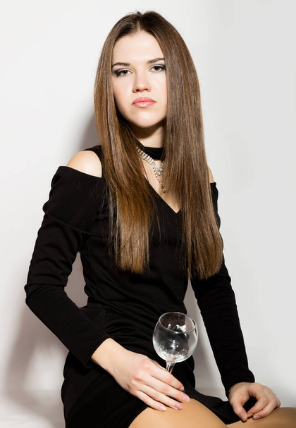 Fashion business beautiful young women in a little black dress with accessories, holding an empty wine glass - 写真・画像