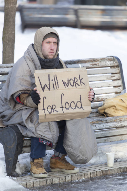   Hombre joven sin hogar hambriento en el parque de invierno de la ciudad en busca de trabajo
 - Foto, Imagen